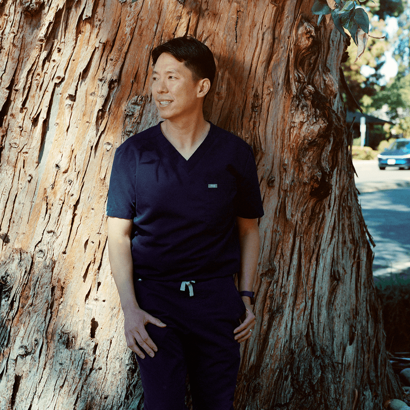 Care professional standing beside a redwood tree